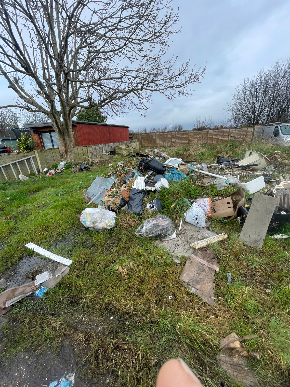 A pile of illegally fly-tipped rubbish, including a mattress and black bags, in a beautiful Hampshire woodland setting.