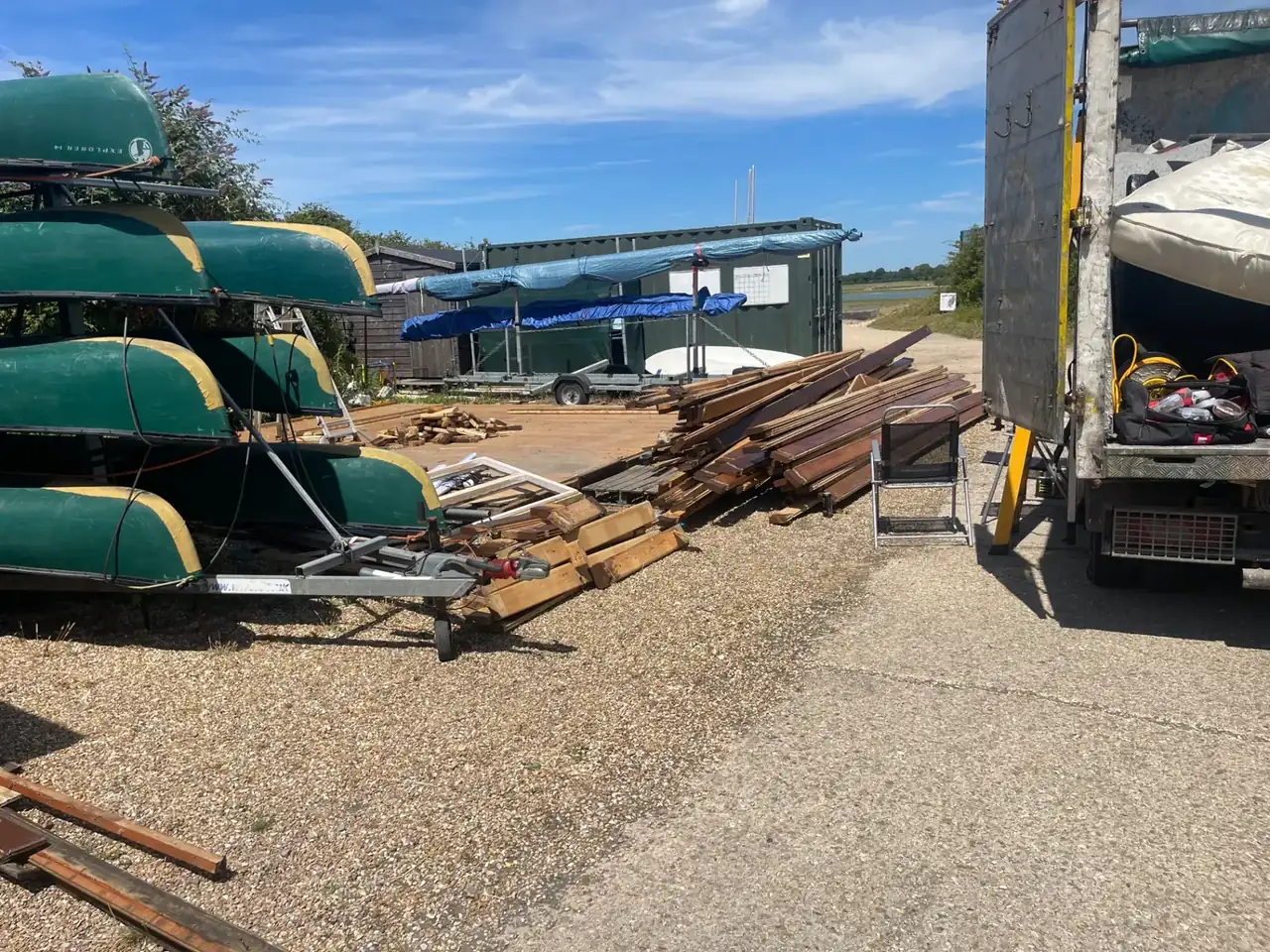Loose timber, boards and site waste beside a tipper truck on a yard